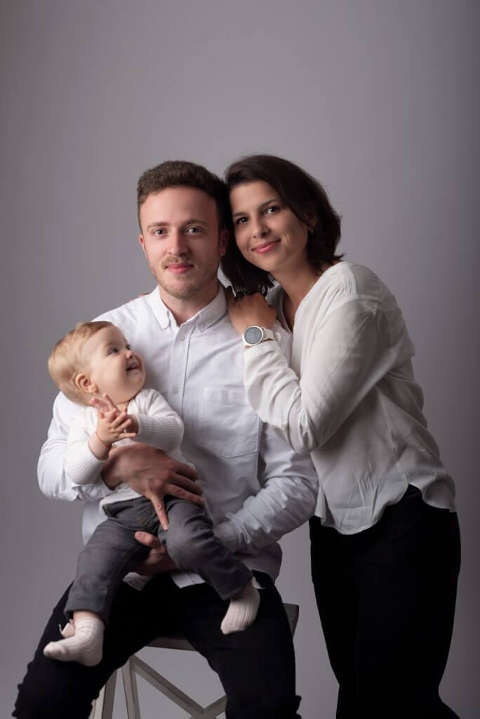 Familie zâmbitoare în haine albe pozează împreună