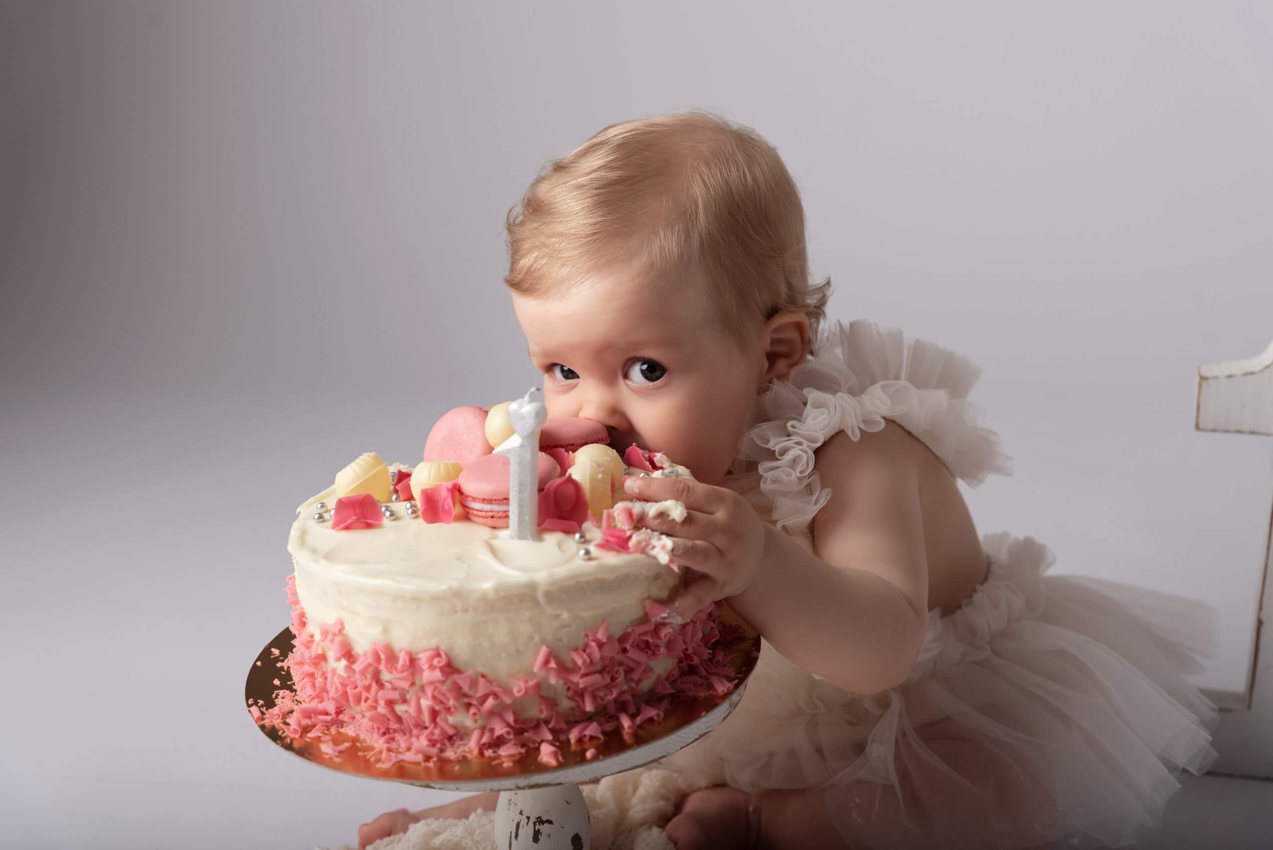 Bebeluș mănâncă tort de ziua de naștere.